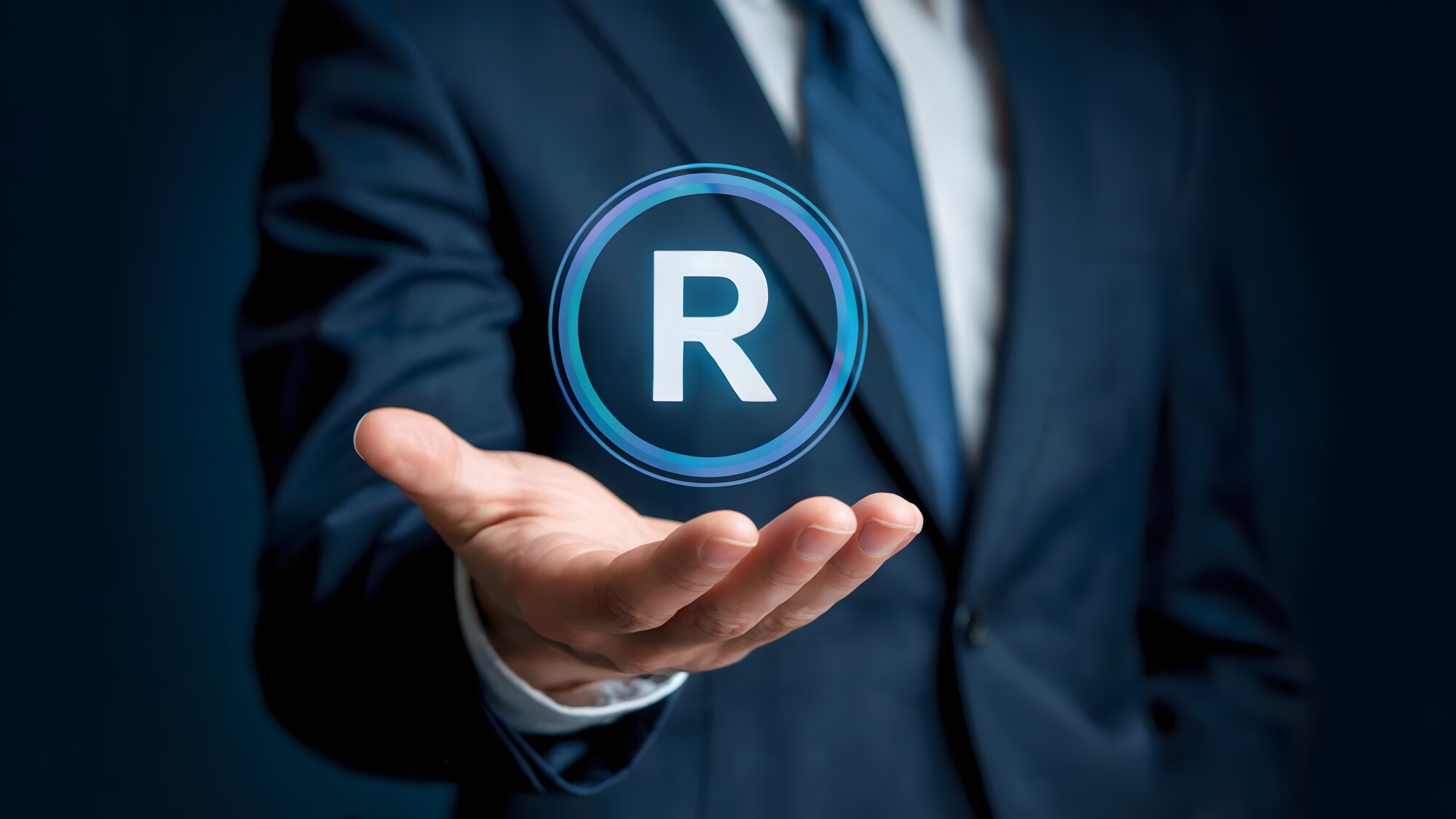 A businessman presents a glowing registered trademark symbol, embodying intellectual property protection and brand ownership in a modern and professional setting for business ventures.
