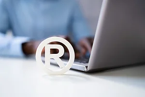 Copyright Symbol Protection Sign. Register Trademark next to laptop with hands typing