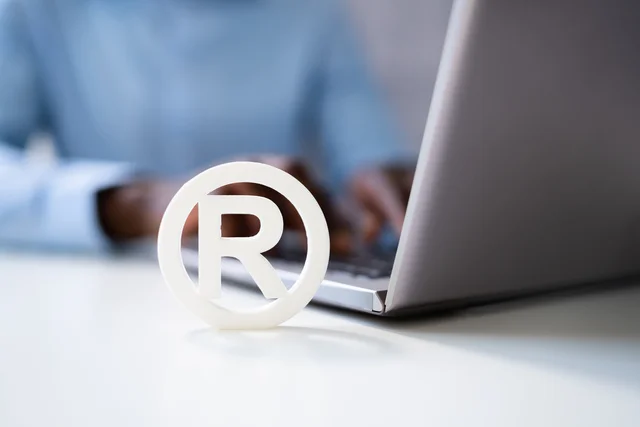 Copyright Symbol Protection Sign. Register Trademark next to laptop with hands typing